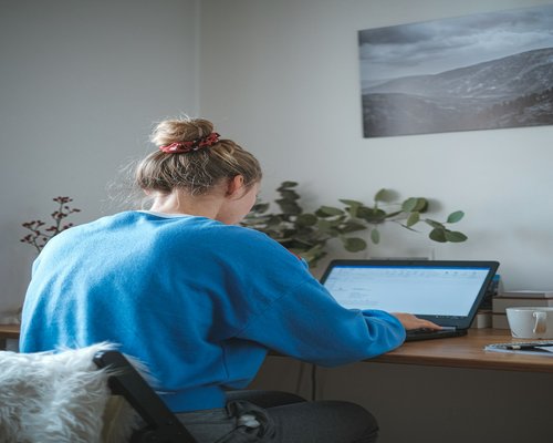 Woman stretching her back while sitting at her home desk